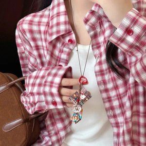 Detail of Hello Kitty acrylic geometric pendant necklace on a red plaid shirt