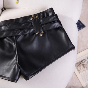 Detailaufnahme der schwarzen PU-Leder Hotpants mit Goldnieten und breitem Gürtel