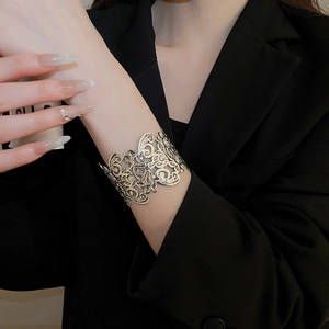 Detail of wide open cuff bracelet featuring intricate lace flower hollow patterns