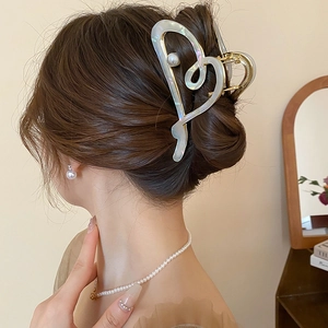 Pince à cheveux élégante en forme de cœur doré avec perle sur une coiffure chic