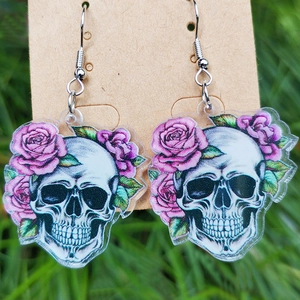 Acryl-Ohrringe mit Totenkopf, lila Rosen und grünen Blättern auf natürlichem Grashintergrund