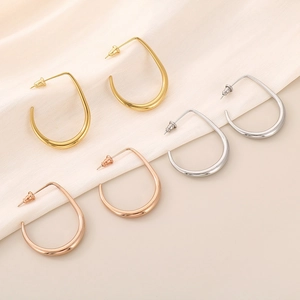 Three pairs of U-shaped metal earrings in gold, silver and rose gold on beige fabric
