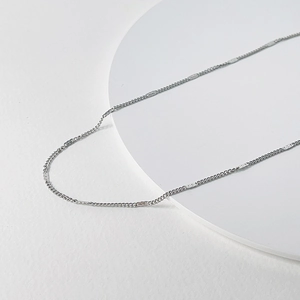 Macro detail of high-polished silver titanium steel chain necklace on white pedestal
