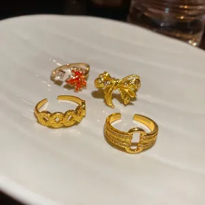18k gold plated open rings set with maple leaf, bow, and zircon on white porcelain