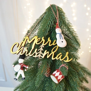 Wooden Merry Christmas plaque with nutcracker and snowman ornaments on a festive tree