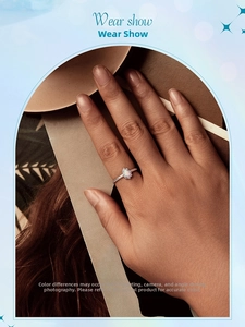 Pear-cut aurora opal ring in s925 sterling silver worn by a model on a wooden base