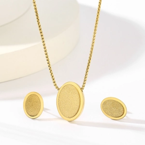Detail of gold oval jewelry set featuring matte textured necklace and stud earrings