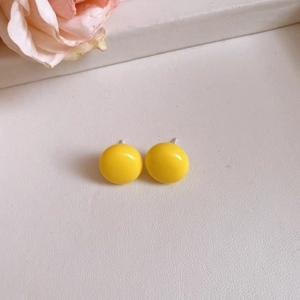 Vibrant yellow round resin stud earrings with silver pins for a modern look.
