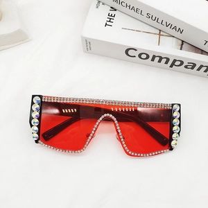 Détail de lunettes de soleil surdimensionnées à verres rouges avec monture en strass