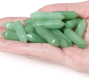Close-up of polished green crystal hexagonal double-pointed prisms held in hand