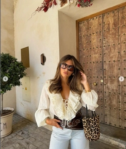 Detail view of beige ruffle V-neck blouse with long sleeves and tie neck styling