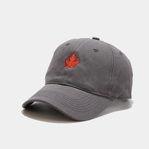 Detailed view of maple leaf embroidery on dark grey cotton baseball cap with ventilation holes