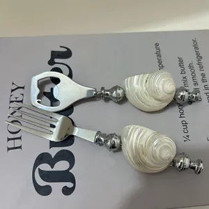 Detailed view of ocean style stainless steel fork and opener with natural conch shell handles