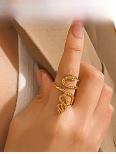 Close-up of golden snake-shaped ring with scale texture worn on a finger