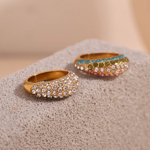 Close-up of two 18K gold plated wide rings with sparkling zircons on a textured stone