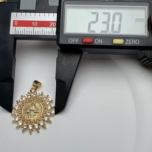 Macro shot showing 23.0mm size measurement of gold sunburst pendant with zircons