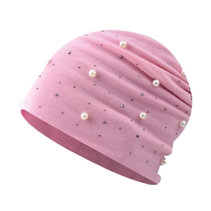 Close-up of pink knitted beanie with delicate white pearls and sparkling rhinestones