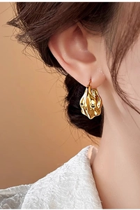 Detail of 18K gold-plated earrings with irregular crumpled texture on model side profile