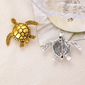 Vue détaillée de face et de dos des broches tortue vintage en finitions or et argent