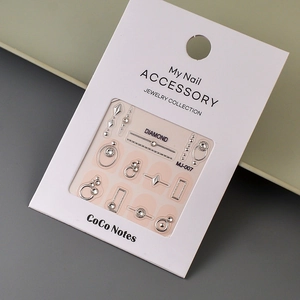 Close-up of silver geometric nail charms with sparkling rhinestones on a display card