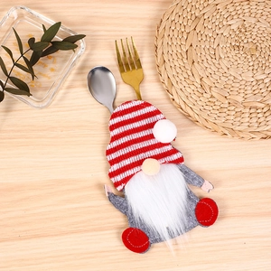 Macro view of Christmas gnome cutlery holder with red striped hat on a rustic table