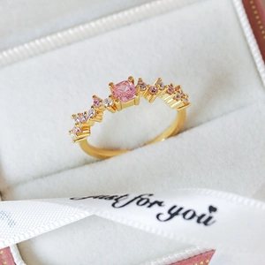 Close-up of pink zircon ring in gift box with wave-shaped band and sparkling stones