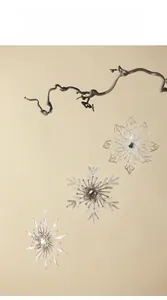 Three clear acrylic snowflake ornaments hanging on natural branches for Christmas decor