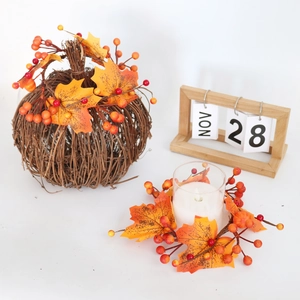 Close-up of woven pumpkin and candle ring with maple leaves and berries for autumn decor