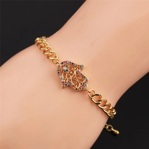 Gros plan d'un bracelet gourmette doré avec breloque main de Fatma en zircon coloré au poignet