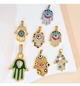 Dettaglio di pendenti a mano di Hamsa colorati in oro e argento con intarsi in zircone