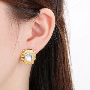 Vintage gold square sunburst earrings with a clear cubic zirconia, shown on ear