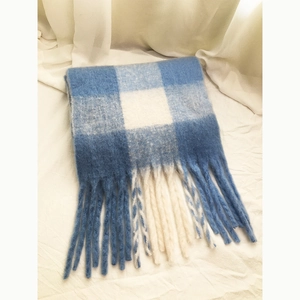 Macro shot of blue and white checkered scarf with soft wool texture and tassel detail