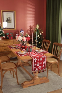Close-up of red Christmas table runner with white snowflake patterns and tassel edges