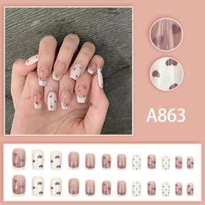 French style press-on nails with red heart and bow designs in nude pink and cream tones