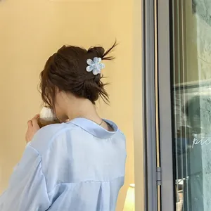 Detail of blue gradient flower hair claw clip with glitter on a braided hairstyle