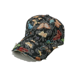 Detailed view of colorful butterfly jacquard embroidery and distressed frayed brim on black cap