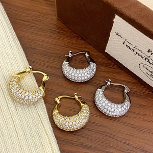 Detailed view of C-shaped gold and silver earrings featuring shimmering micro-pave zircons