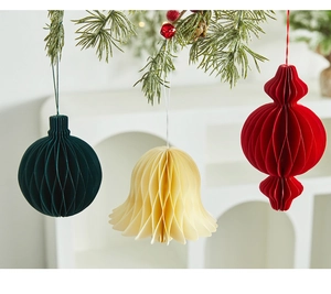 Hanging honeycomb paper Christmas ornaments in green, cream, and red on pine branches