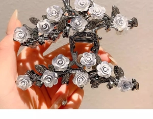 Detail of a large black metal shark hair claw clip with white camellia flowers and crystals