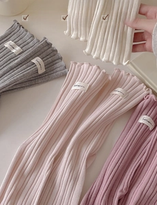 Detail of ribbed cotton socks showing ruffled lettuce trim and decorative fabric label