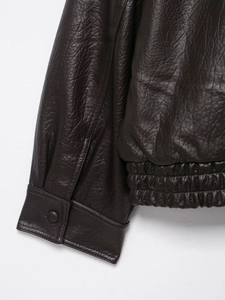 Détail de veste en cuir marron foncé montrant les poignets, l'ourlet et la texture