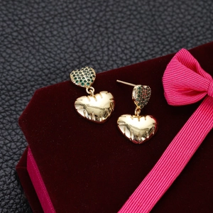 Macro shot of green zircon heart earrings on red velvet with elegant gold ribbing