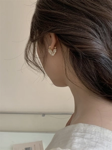 Macro shot of gold-plated heart earrings featuring delicate flower petals and pearls