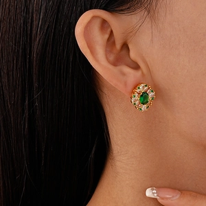Close-up of a floral gold stud earring with a green oval stone on a female model