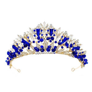 Detailed close-up of golden bridal crown with blue and clear crystals on white backdrop