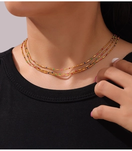 Close-up of layered titanium steel gold necklace with colorful beads on a model