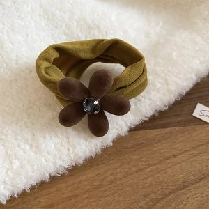 Détail d'un chouchou en velours vert olive avec fleur marron et pierre précieuse brillante