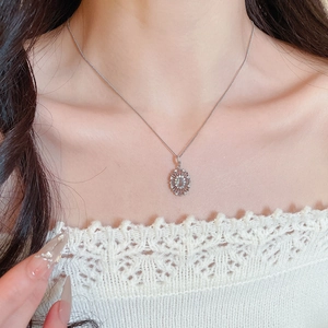 Detail shot of a silver zircon oval sunburst pendant necklace on a female model