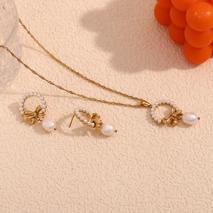 Elegant 18K gold plated bow and pearl necklace and earrings set on a warm background