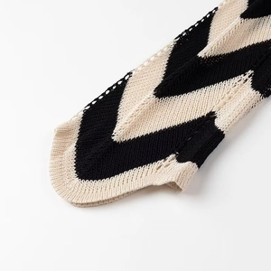 Detailaufnahme des schwarz-weißen Wellenmusters und der feinen Saumnaht des Strickkleids
